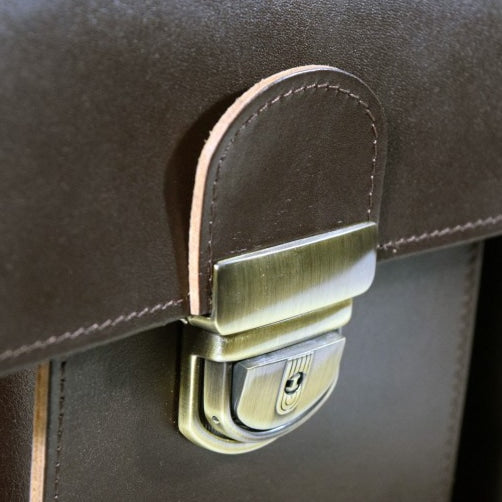 Close-up of brass buckle on dark brown leather Briefcase No. 35, showcasing craftsmanship and durability.