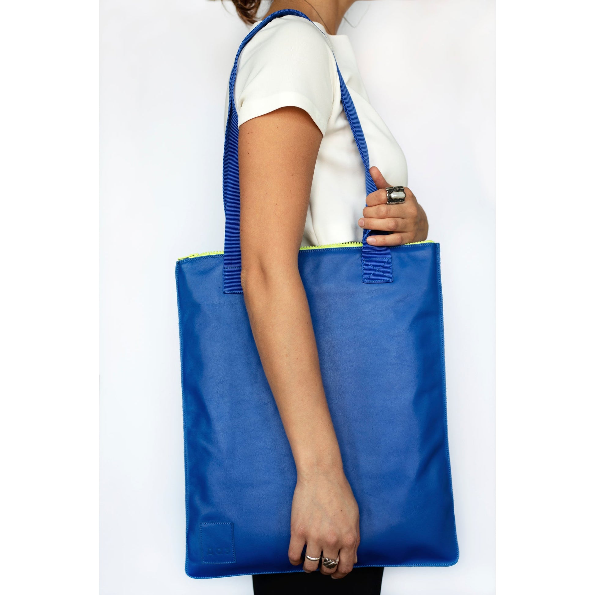 Woman holding a Handmade Leather Tote in royal blue with blue straps, available on USMIH Grid. Purchase with card or Bitcoin for a modern look.