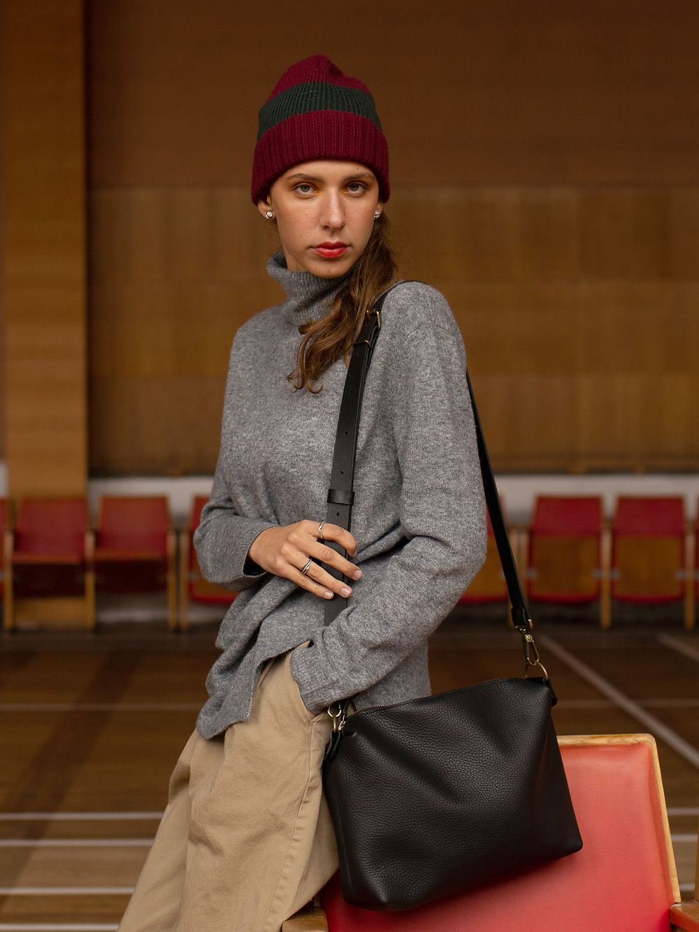 Woman with black leather ROBIN handbag wearing a beanie and sweater, showcasing TOKS VISOKS on USMIH Grid, available with cryptocurrencies.