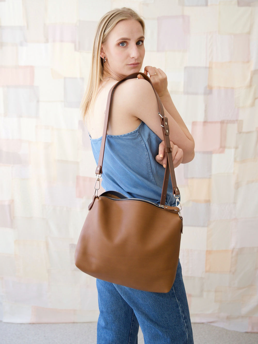 Stylish woman holding a camel brown ROBIN leather handbag, available at the modern USMIH Grid marketplace with card and cryptocurrency options.