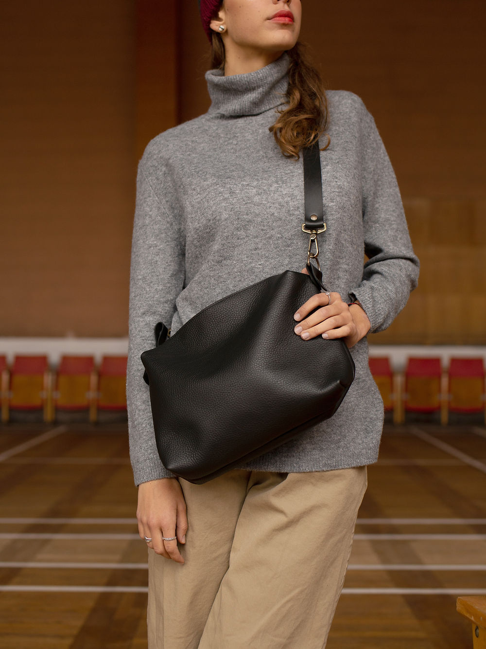 Woman showcasing the ROBIN Large Black Leather Handbag with adjustable strap, available on USMIH Grid. Buy with card or cryptocurrency.