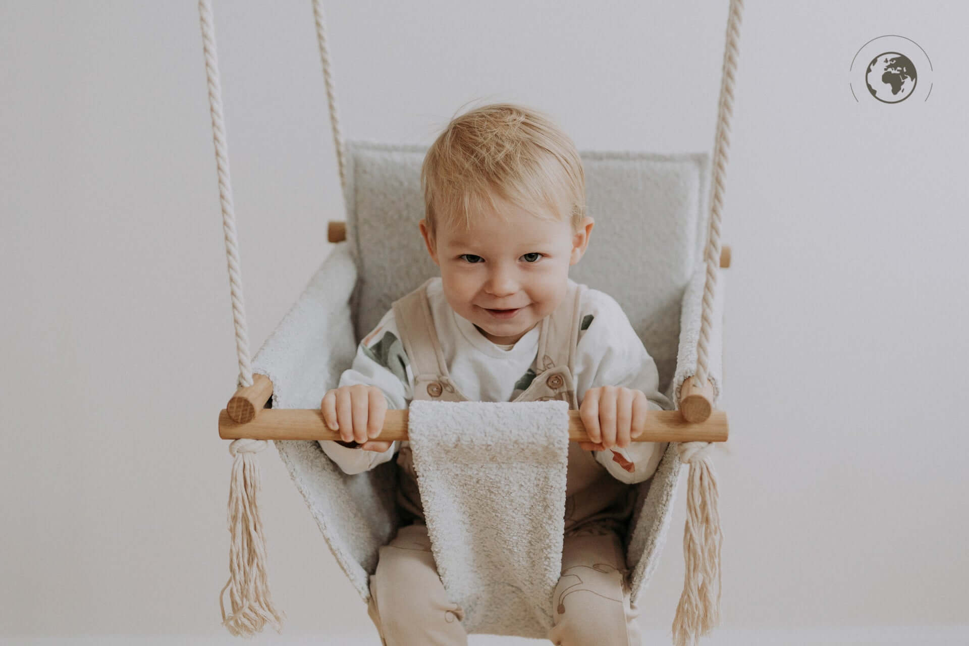 Toddler smiling in BaBi Baby Swing Bouclé Ice Grey, eco-friendly and safe, available at USMIH Grid with card and Bitcoin payments.