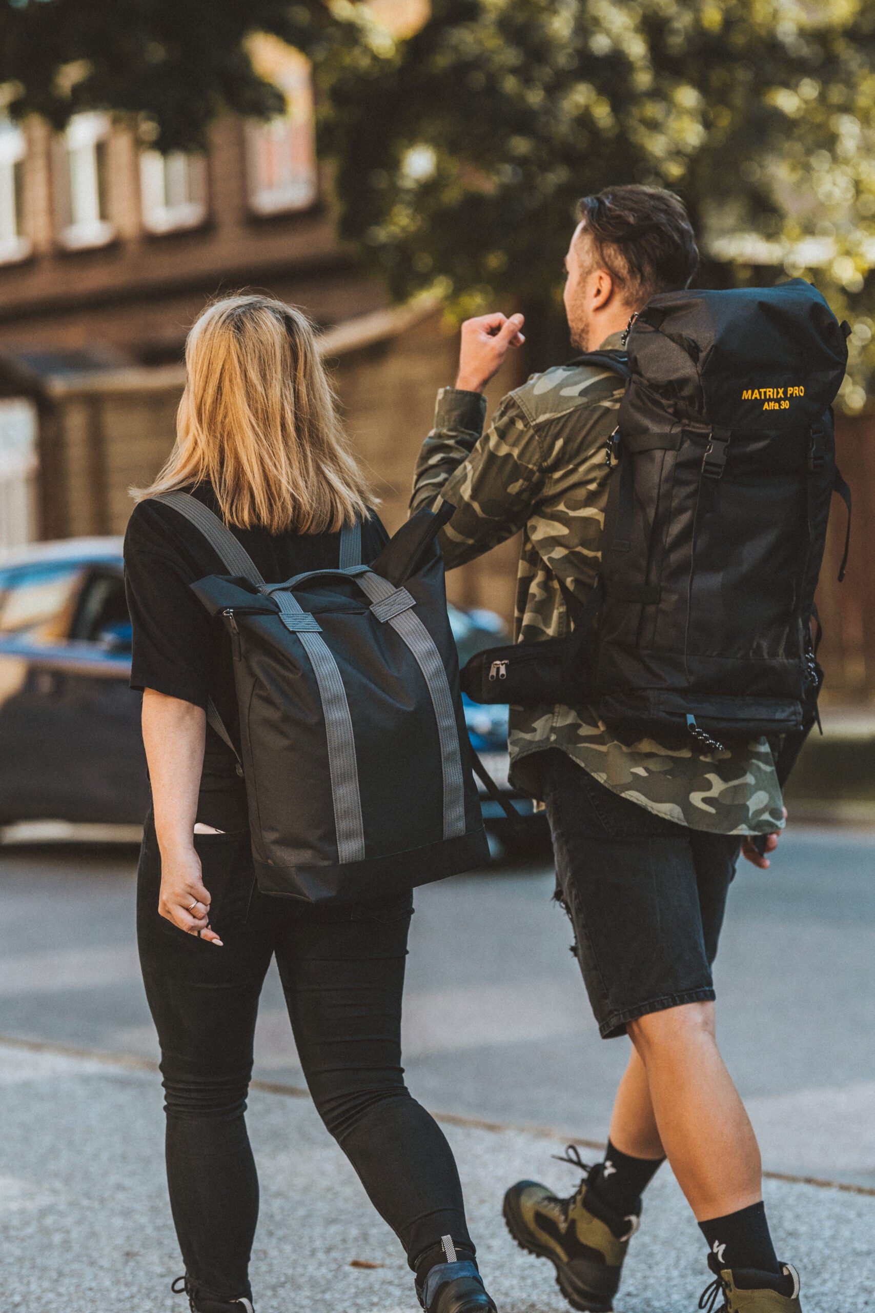 Couple walking with Alfa 30 Hiking Bag and Matrix Pro backpack, showcasing versatile everyday and hiking use, featuring USMIH Grid design.