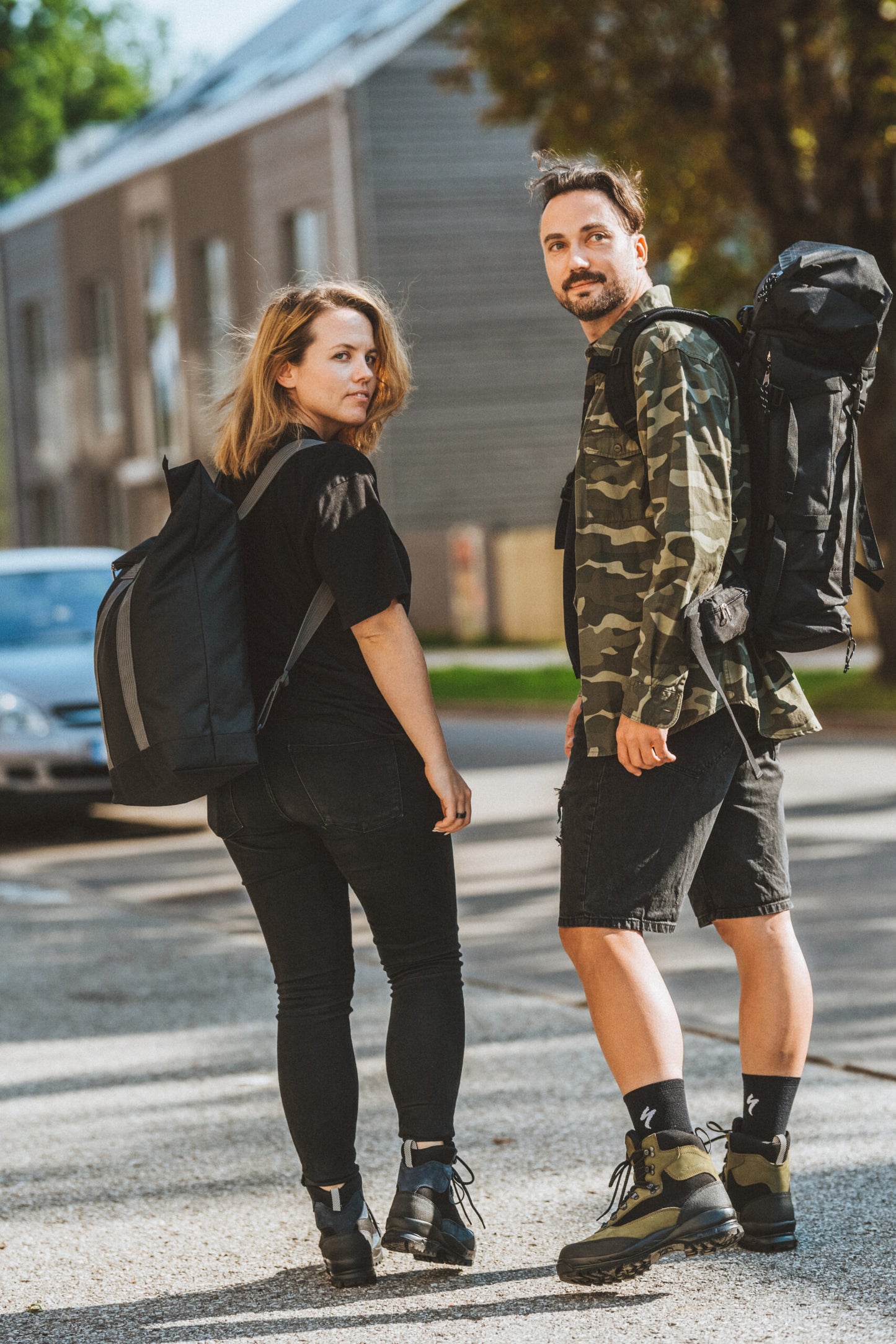 Two people carrying Alfa 30 Hiking Bags with USMIH Grid design outdoors near buildings.