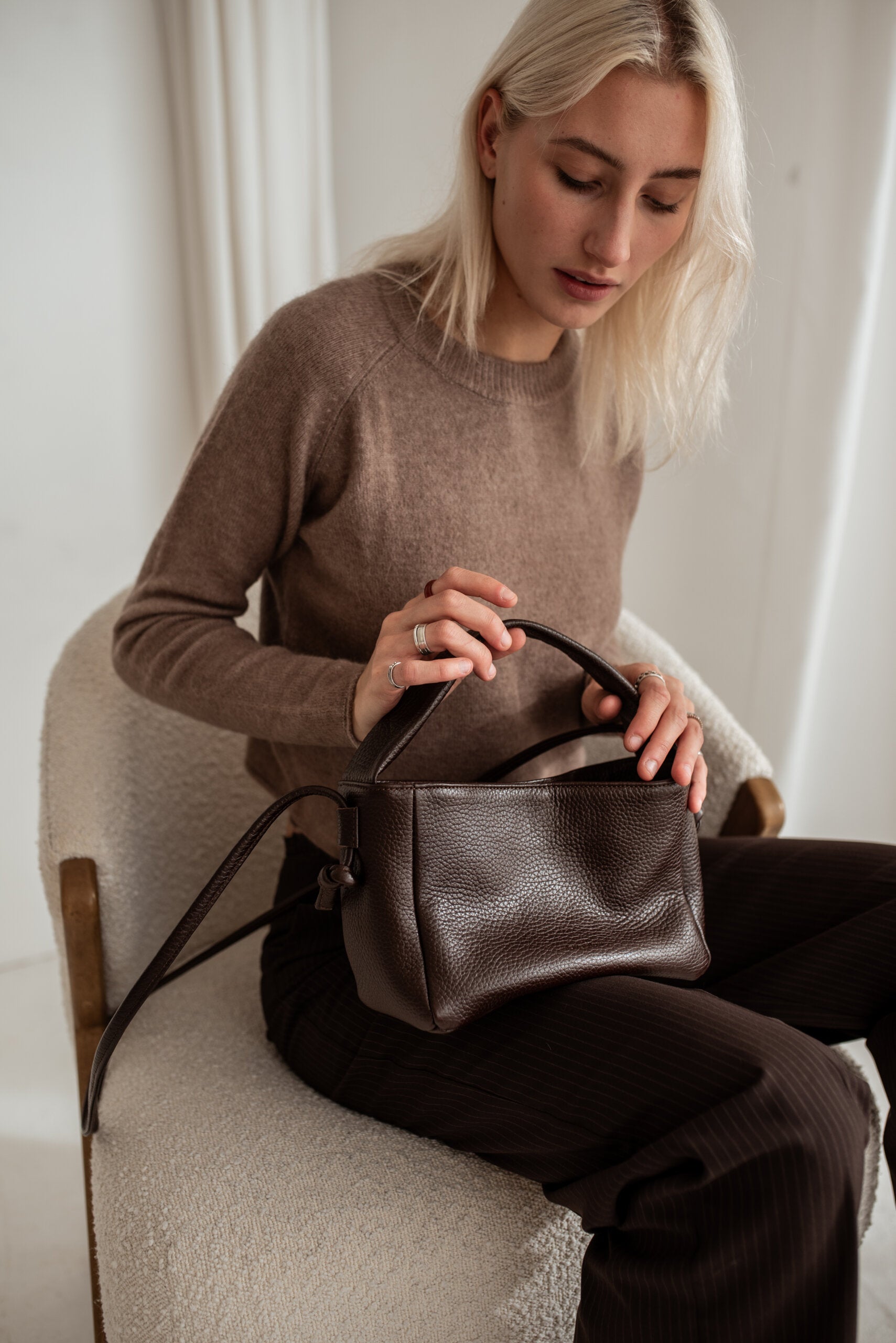 Woman holding minimalist dark brown crossbody bag Meru, showcasing adjustable strap, luxury present idea, available at USMIH online with crypto.