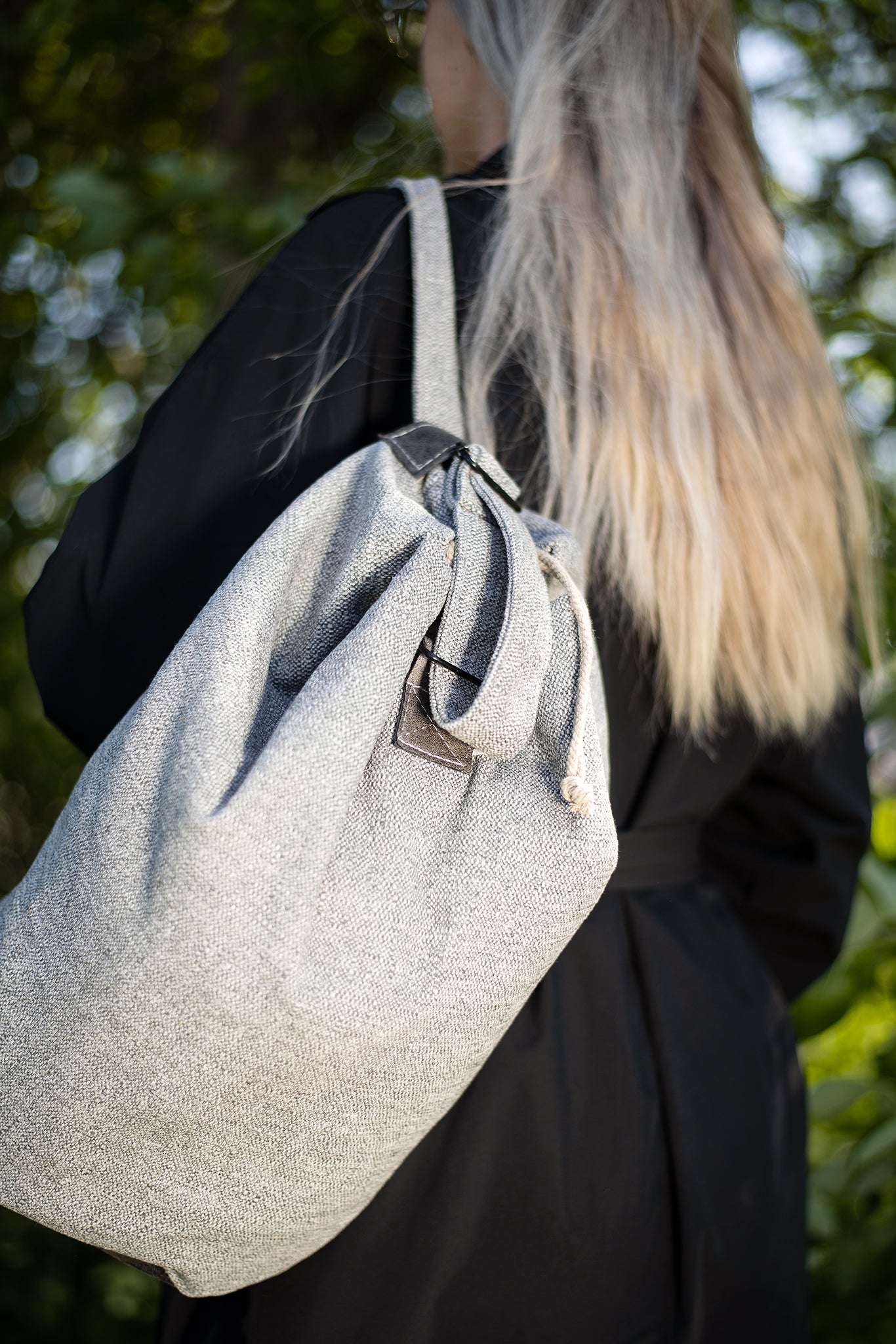 Person wearing a light grey Märss upcycled bag made from durable leftover fabric and faux leather, featuring a unique handmade design.