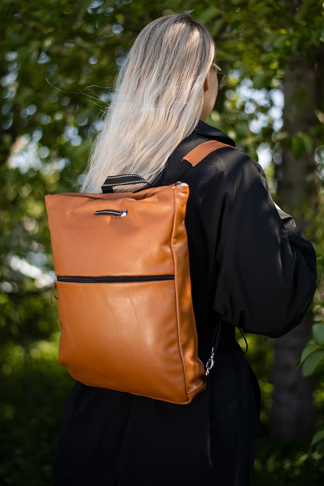 Woman wearing Barbara Leather Backpack - Calvados in a natural outdoor setting. High-quality, handmade, sustainable leather backpack with multiple compartments.