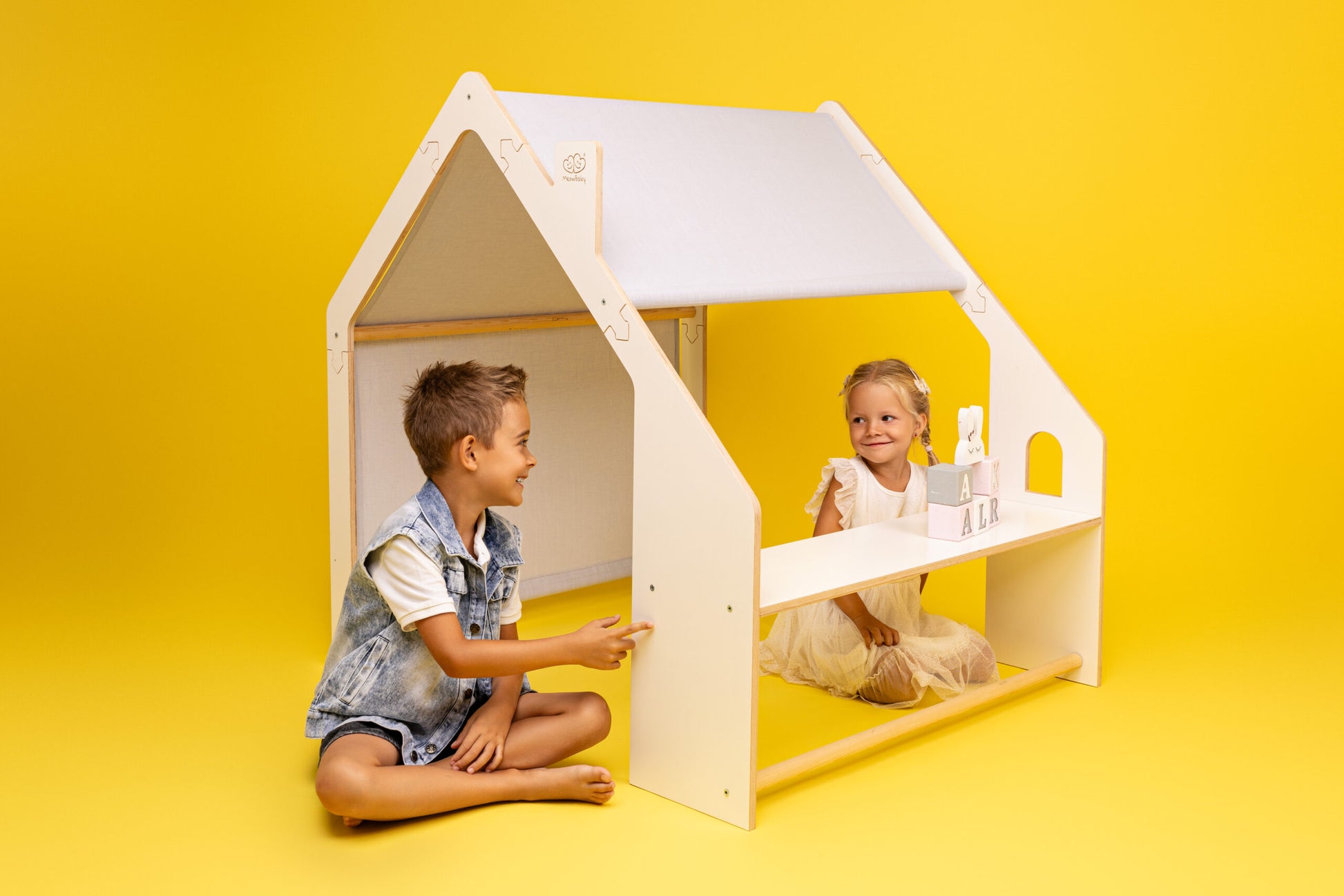 Two children playing in a MeowBaby White Wooden House with Blue Roof on a yellow background. Perfect for unique, stylish gifts | Find USMIH.