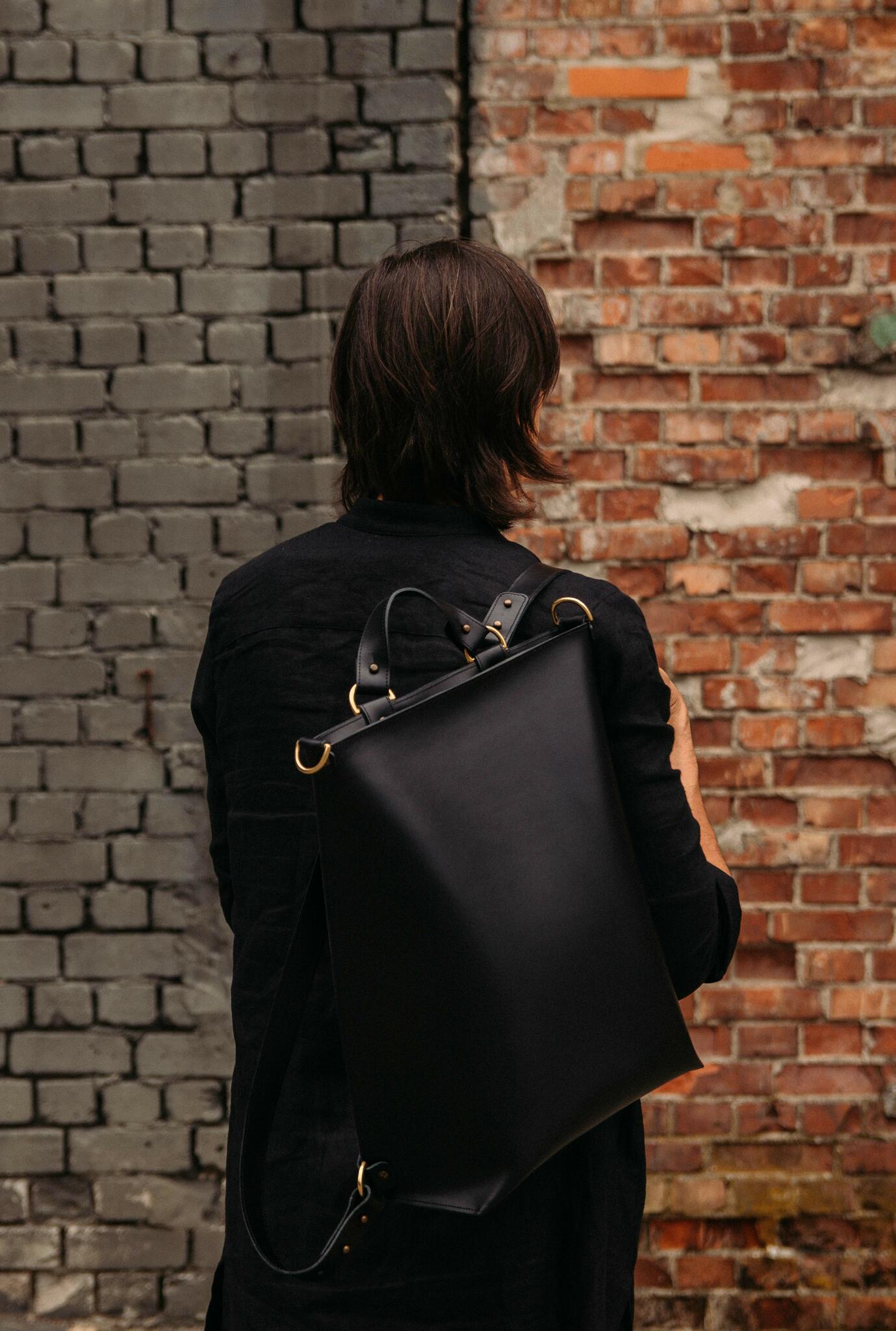 Sleek black leather backpack worn by person, ideal for modern style. Buy online with card or crypto on USMIH Grid, luxury European brand.