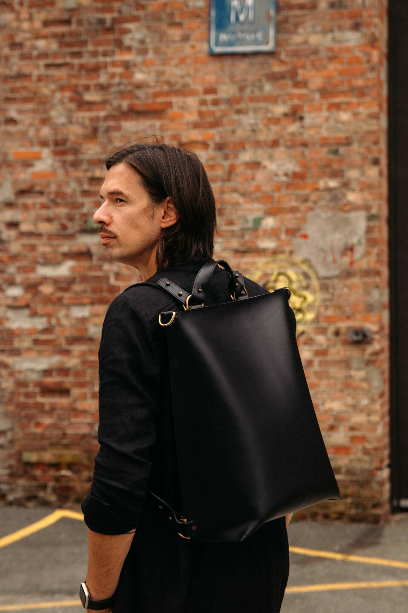 Stylish man carrying Stella Soomlais multifunctional leather backpack, available for card and crypto payments on USMIH Grid.