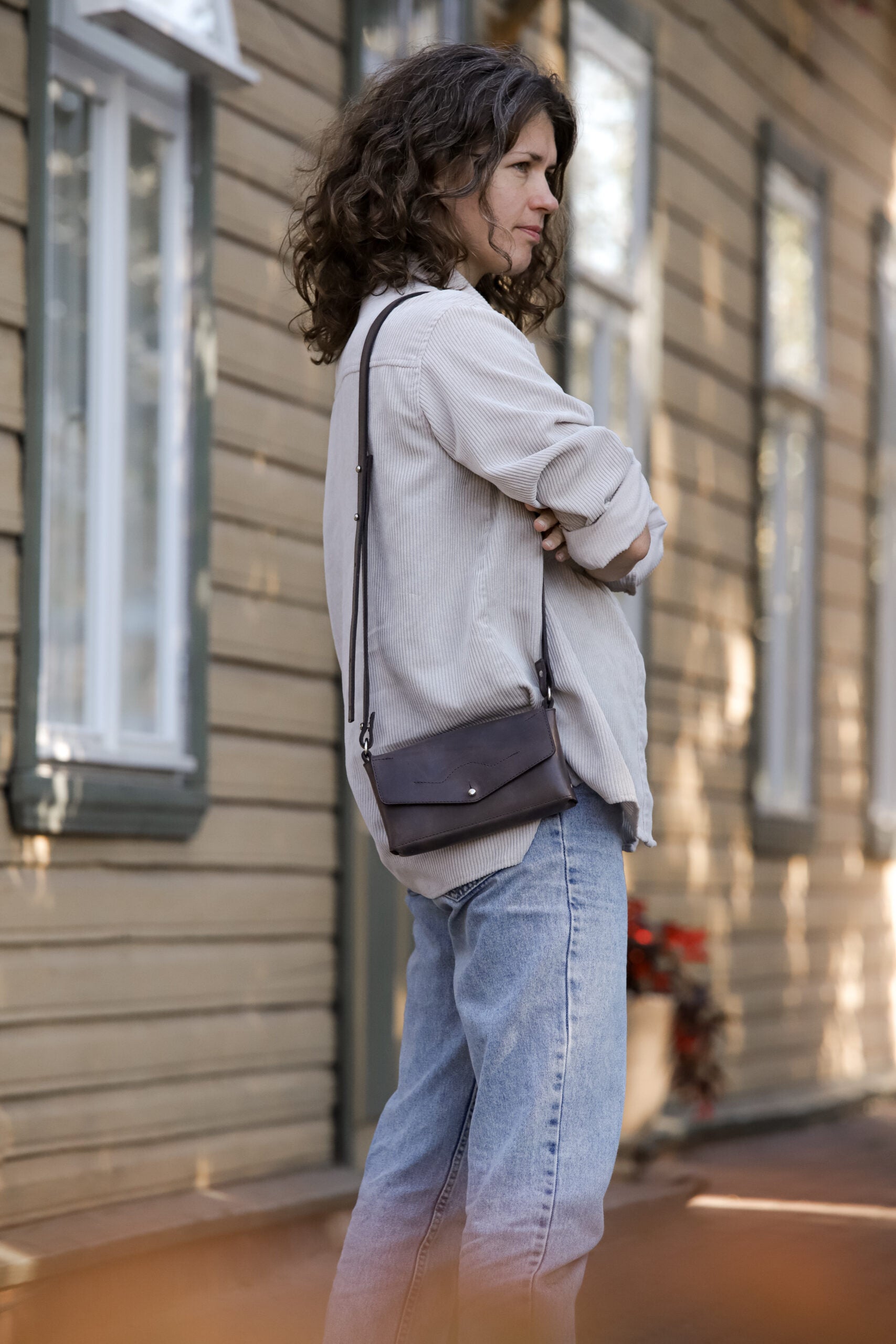 Woman wearing Crossbody Leather Bag KOKUKA outside; versatile, stylish gift idea available on USMIH for online purchase with crypto.