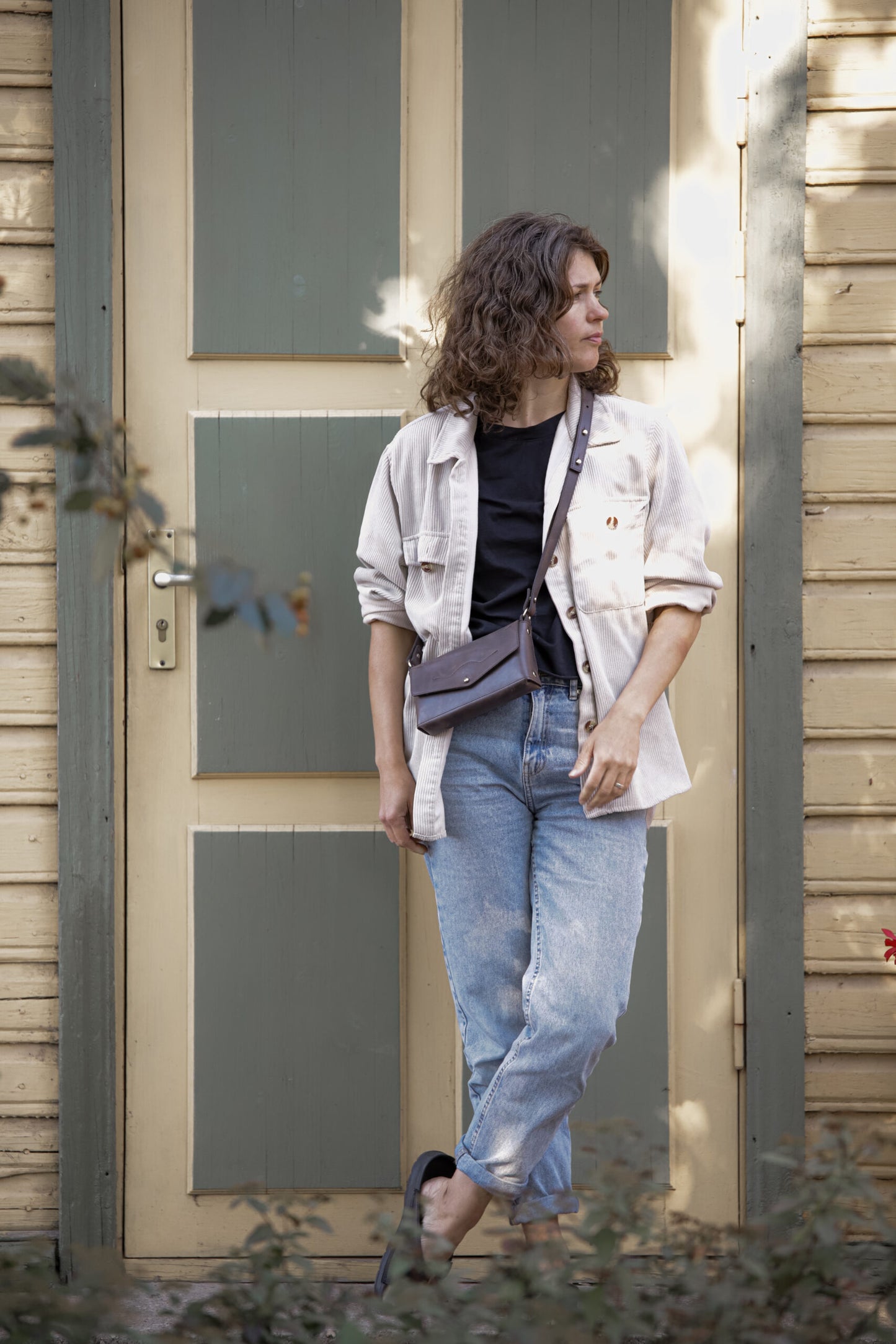 Woman wearing KOKUKA crossbody leather bag outdoors in casual attire, showcasing versatile style options.