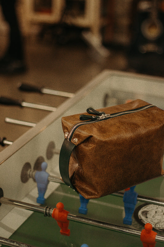 Large leather toiletry bag on foosball table, available on USMIH Grid, supports card, Bitcoin, and altcoin payments.