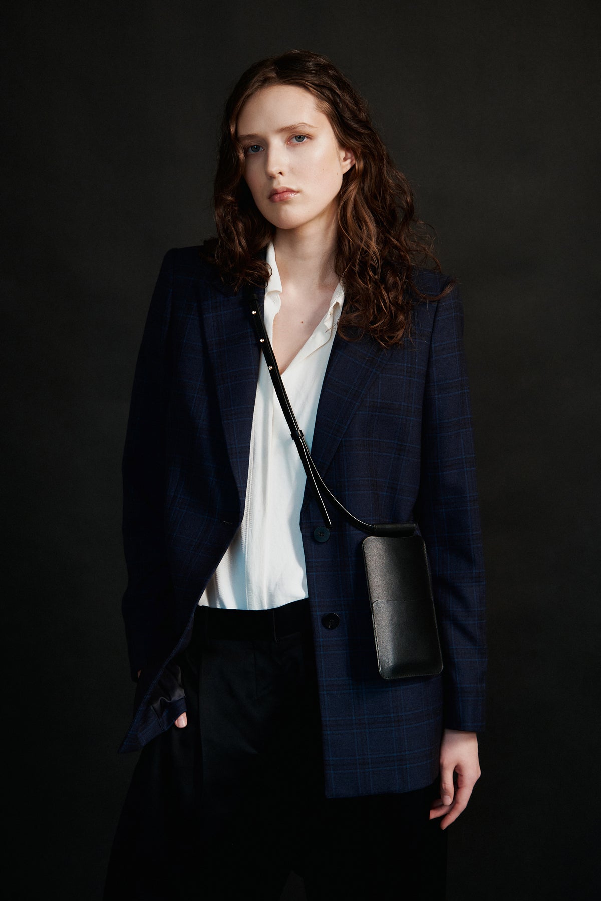 Woman wearing black leather crossbody phone bag, styled with blazer, available on USMIH Grid, accepts card and cryptocurrency payments.