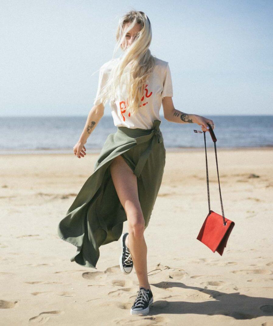 Fashionable woman on beach carrying USMIH Grid red chain shoulder bag, showcasing style and versatility.