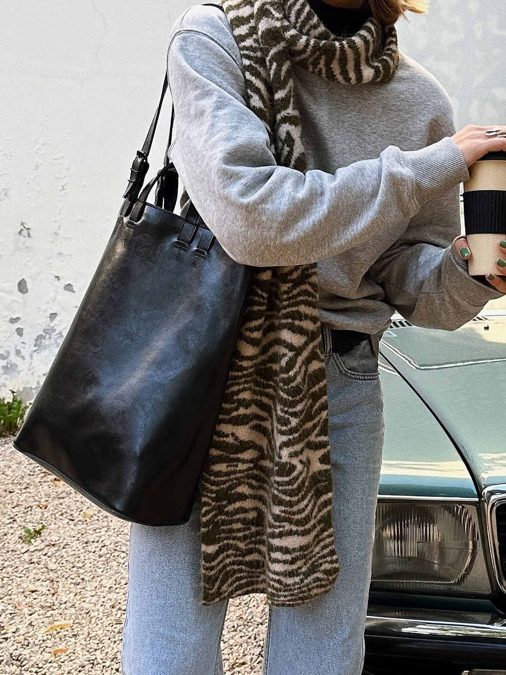 Stylish leather tote bag from USMIH Grid carried by person in casual wear, holding a coffee, showcasing chic urban style.