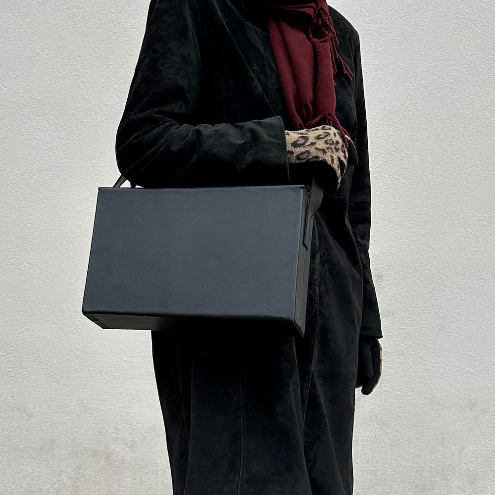 Elegant Leather Box Bag held by model, showcasing USMIH Grid simplicity and timeless style against a minimalist background.