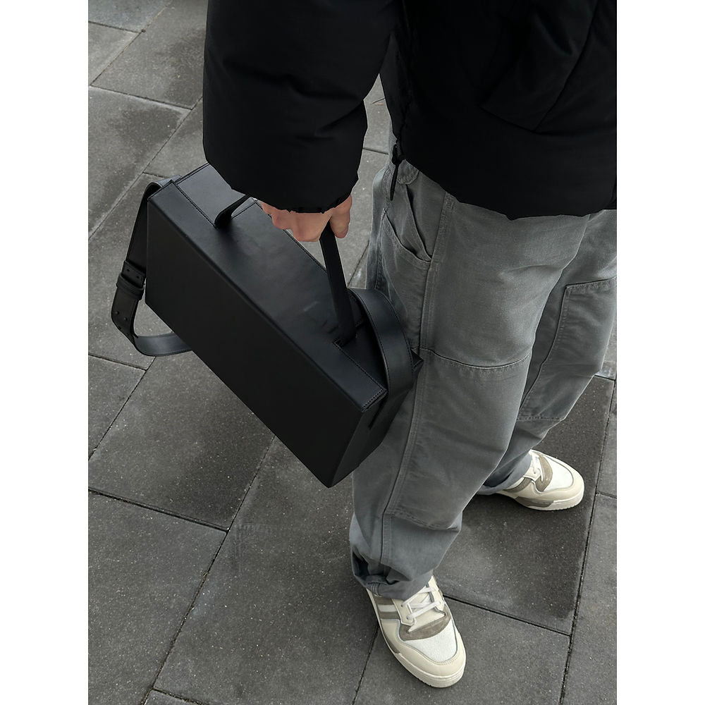 Person holding USMIH Grid Leather Box Bag, showcasing its sleek elegance and solid design for modern style and durability.