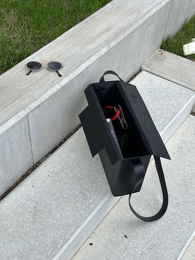 Sleek Leather Box Bag with USMIH Grid design on modern stone steps, showcasing a blend of elegance and functionality.