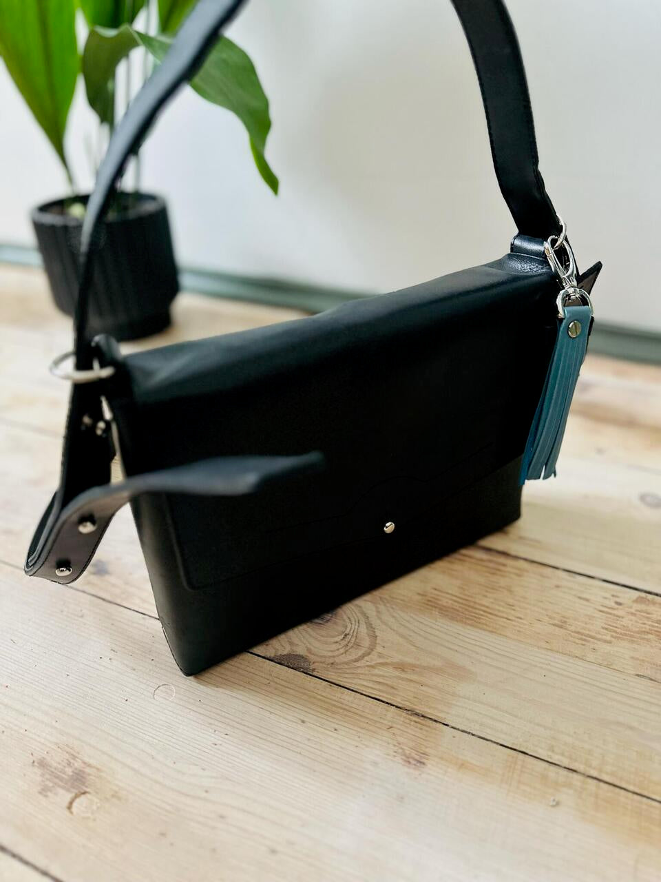 Crossbody black leather KOKUKA bag on wooden table, versatile luxury gift idea for men, available on USMIH Grid with Bitcoin payments.