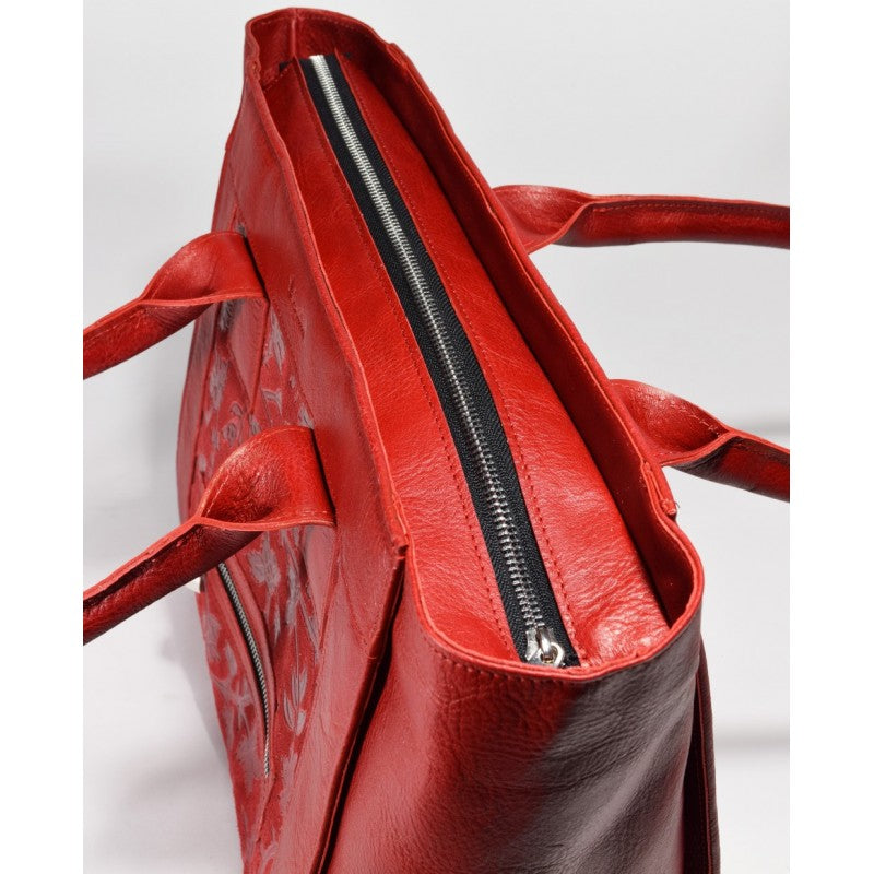 Close-up view of a red leather handbag with a top zipper and sturdy handles.