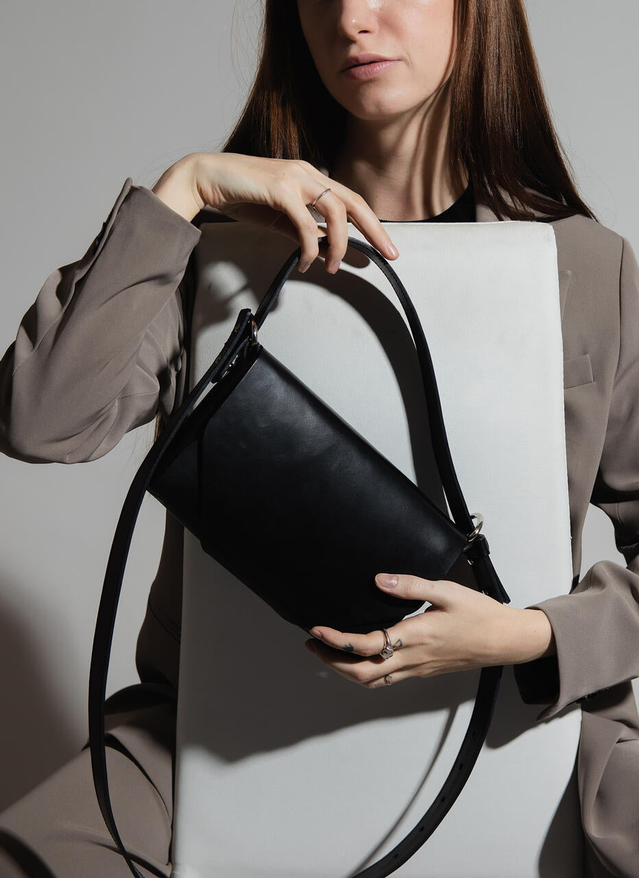 Black leather fanny bag held by a person in a modern setting, available on USMIH Grid for online purchase with card or crypto payments.