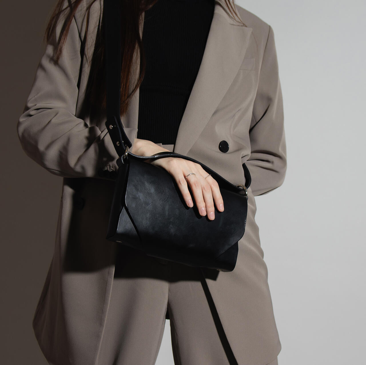 Capital of Goods Black Leather Fanny Bag, stylishly held by a woman in a beige suit, available on USMIH Grid.