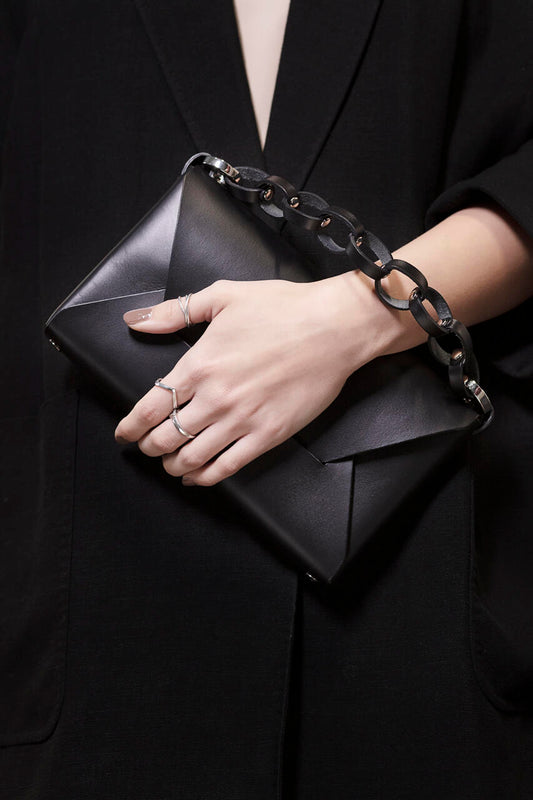 Black leather evening bag with chain strap, crafted by Stella Soomlais, available for online purchase with crypto on USMIH Grid.