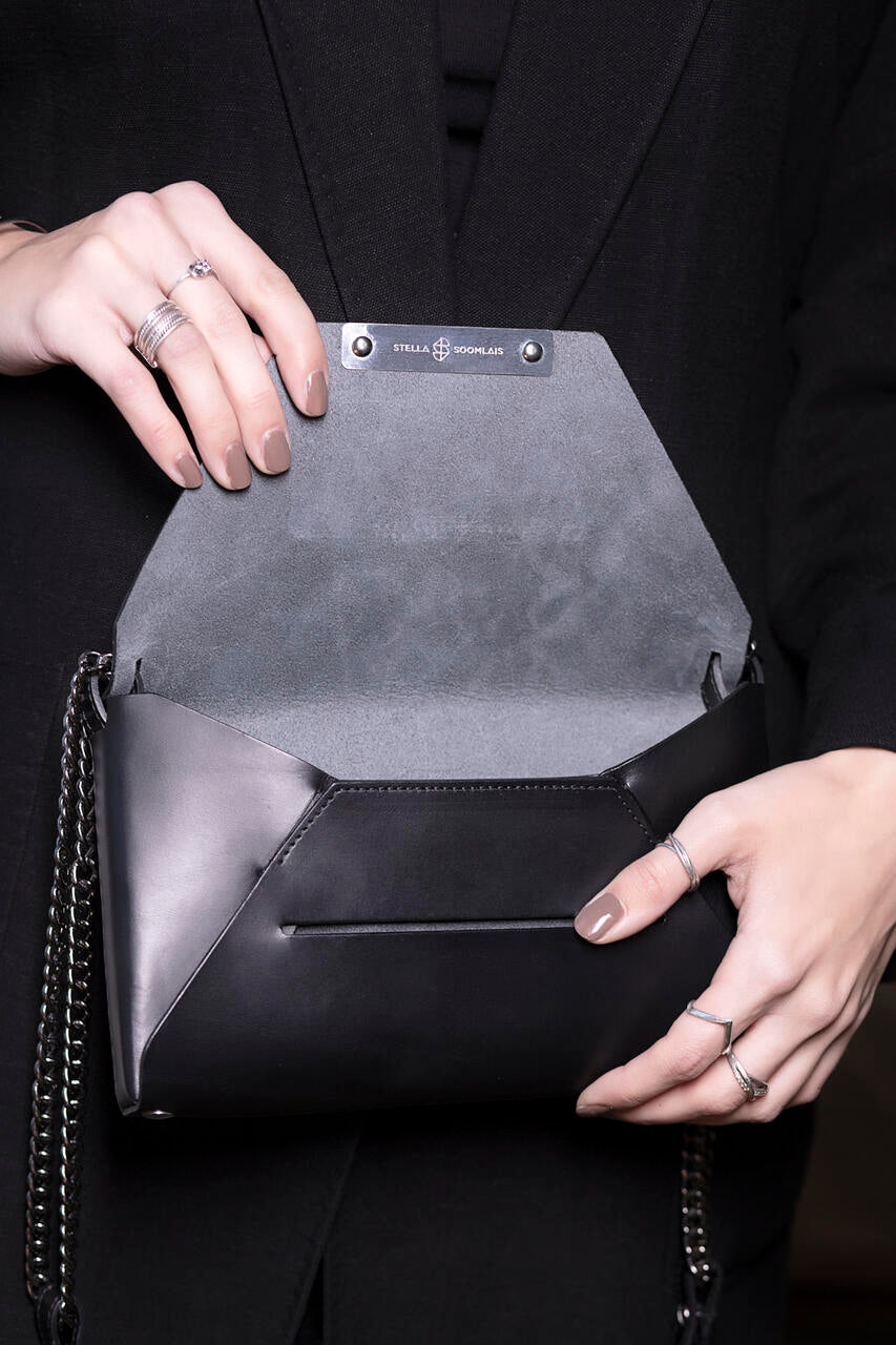 Woman holding Stella Soomlais black leather evening bag with open magnetic closure, highlighting craftsmanship on USMIH Grid.