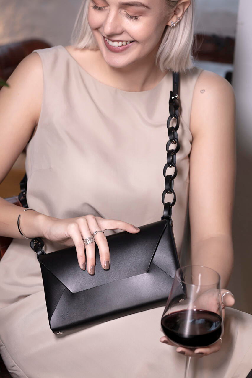 Woman holding Stella Soomlais Wine & Dine evening bag in black, with magnetic closure, perfect for modern occasions on USMIH Grid.