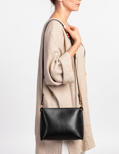 Black leather "Take A Short Day Off" handbag with adjustable strap, showcased on a model. Available on USMIH Grid for card and crypto payments.