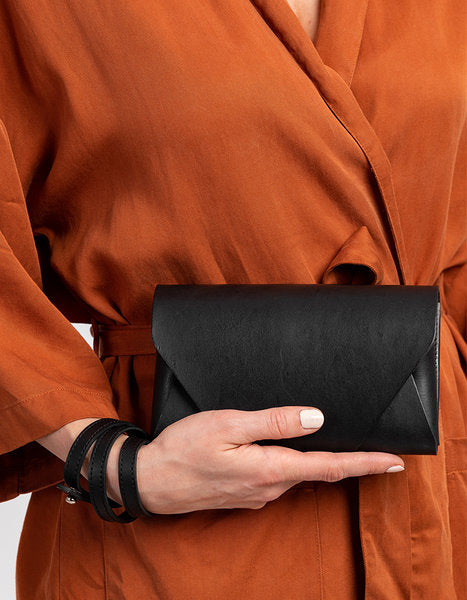 Black leather clutch wallet by Stella Soomlais, versatile with removable straps, available online with crypto payments. USMIH Grid | Join the Grid!