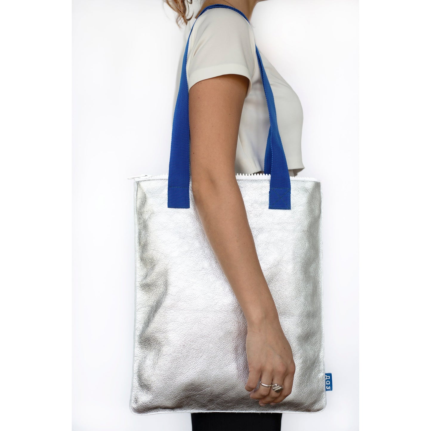 Silver handmade leather tote with blue straps on model, available on USMIH Grid. Buy with card or Bitcoin, supporting European brands.