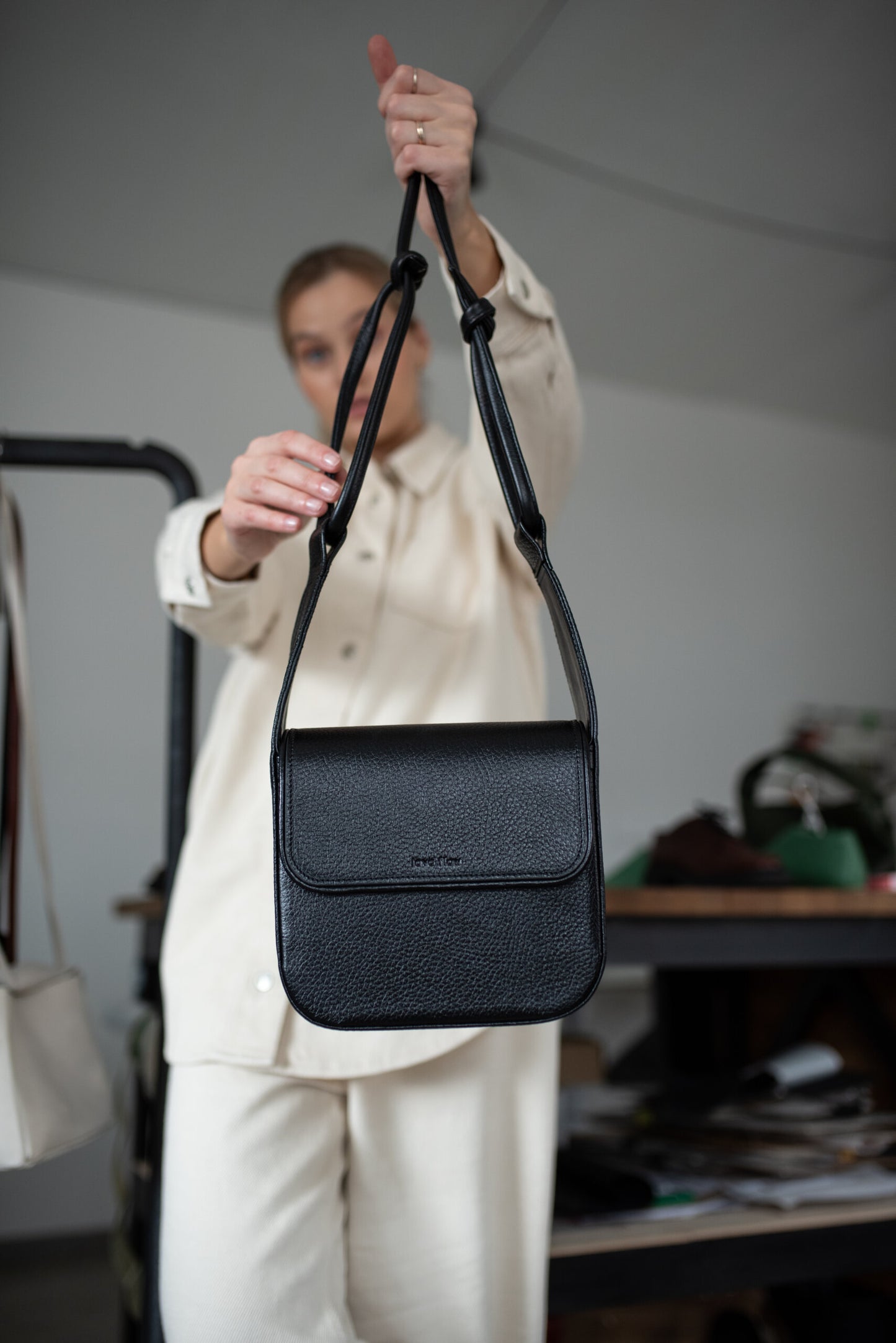 Stylish black MUSA crossbody bag made from premium Italian vegetable tanned leather, held by a person. Ideal luxury gift.